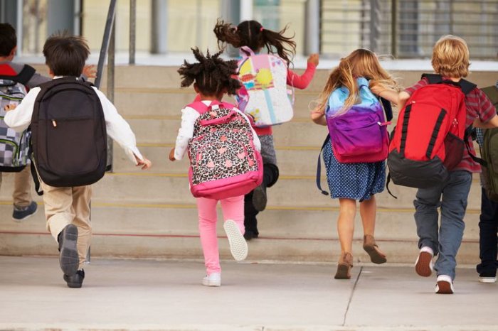 Děti utíkající do školy se školními batohy na zádech
