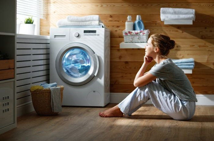 Žena pozorujúca prací cyklus v spredu plnenej práčke