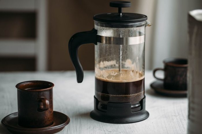 French press kávovar se šálky na stole